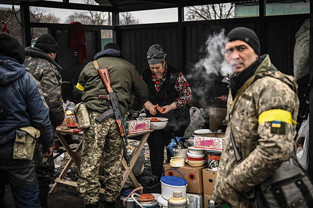 A woman cooks for Ukrainian volunteer soldiers at a frontline, northeast of Kyiv. By Aris Messinis / AFP Via Getty Images