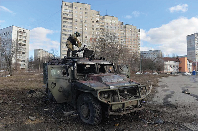 A Ukrainian fighter examining a destroyed Russian armored personnel carrier in Kharkiv on Sunday. By Sergey Bobok/Agence France-Presse/Getty Images
