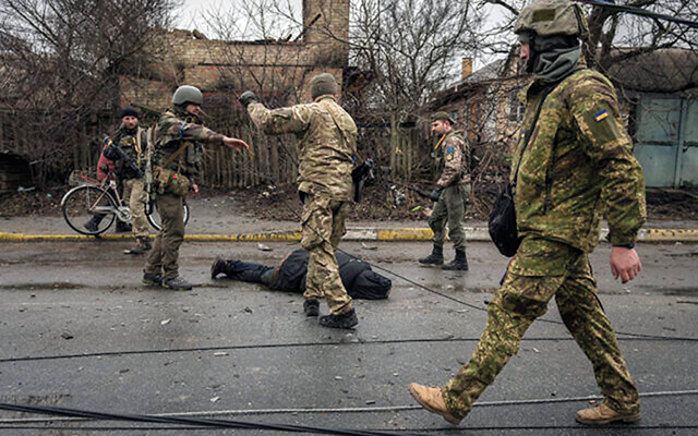 Ukrainian servicemen attach a cable to the body of a civilian while checking for booby traps in the formerly Russian-occupied Kyiv suburb of Bucha, Ukraine, April 2, 2022. Source: AP Photo/Vadim Ghirda