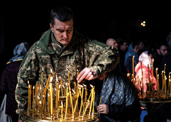 A Ukrainian soldier lights a candle during an Orthodox Easter service in St. Volodymyr's Cathedral. Source: AFP via GETTY IMAGES