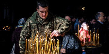 A Ukrainian soldier lights a candle during an Orthodox Easter service in St. Volodymyr's Cathedral. Source: AFP via GETTY IMAGES