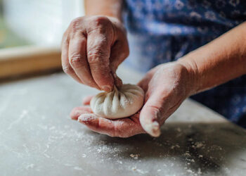 Khinkali being handmade in Georgia with its famous pleated knot on top to close the creation. By Kelsey Petrie