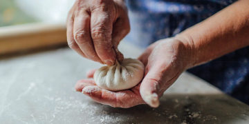 Khinkali being handmade in Georgia with its famous pleated knot on top to close the creation. By Kelsey Petrie