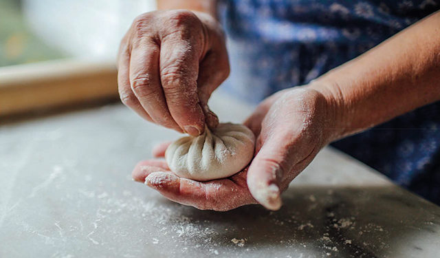 Khinkali being handmade in Georgia with its famous pleated knot on top to close the creation. By Kelsey Petrie