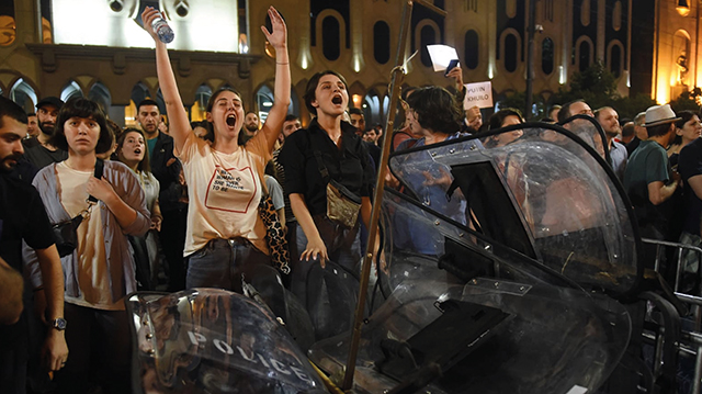 Georgian teenagers shouting slogans with a pile of captured Ministry of Internal Affairs riot shields in front of Parliament in 2019. By Vano Shlamov