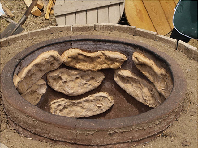 Bread being baked slowly in a tone oven at the Elkana wheat farm facility during a special event. Photo by Mike Godwin