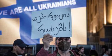A man holding a poster saying ‘deport Russians’ at a 3 April pro-Ukraine rally in central Tbilisi. Photo by Mariam Nikuradze/OC Media.