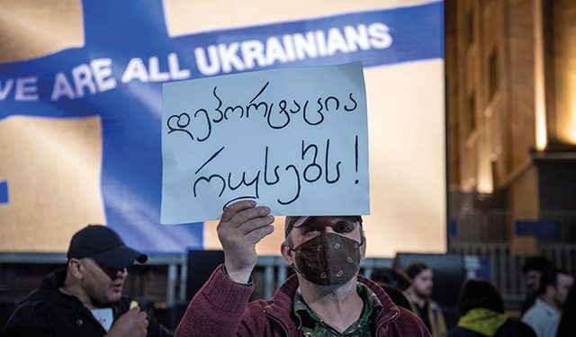 A man holding a poster saying ‘deport Russians’ at a 3 April pro-Ukraine rally in central Tbilisi. Photo by Mariam Nikuradze/OC Media.