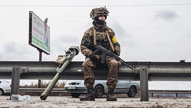 A Ukrainian soldier rests on the side of the road with an anti-air missile system. Photo by Diego Herrera/Xinhua