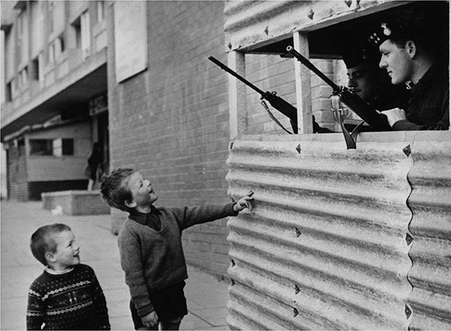 Two young boys smile at British soldiers on patrol on Ulster Street in Belfast on April 20, 1971. By Chris Ware/Getty Images