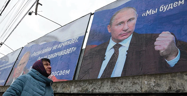 Posters bearing images of Russian President Vladimir Putin and reading "Russia does not start wars, it ends them" (left) and "We will aim for the demilitarization and denazification of Ukraine.” Source: Stringer/AFP via Getty Images
