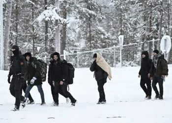 Finnish border guard officers escort migrants upon arrival at the Raja-Jooseppi border crossing station to Russia in Inari, northern Finland, on November 25, 2023. (Photo by Emmi Korhonen / Lehtikuva / AFP)