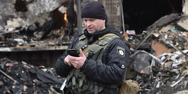 A Ukrainian police officer checks his smartphone following a missile strike in Kyiv. Source: AFP