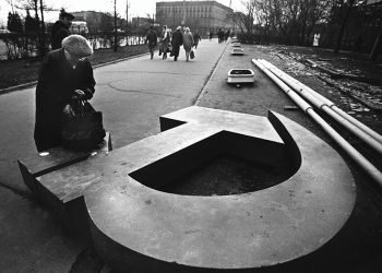 A woman reaches into her bag, which rests on a fallen Soviet hammer-and-sickle on a Moscow street in 1991. Source: The Atlantic