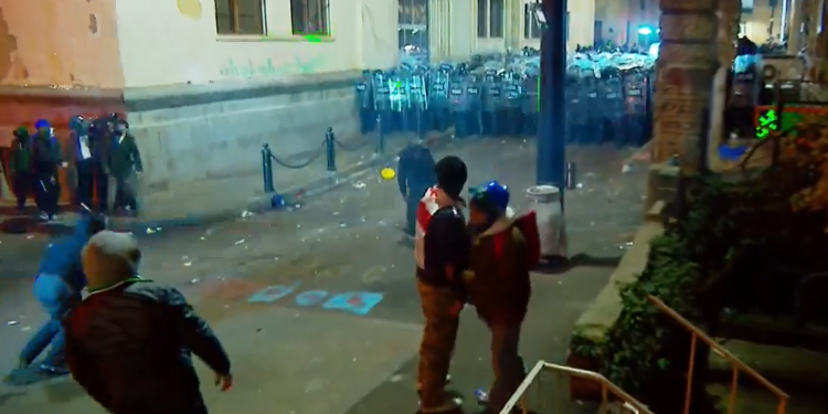 Protesters throw bottles, fireworks at riot police behind parliament