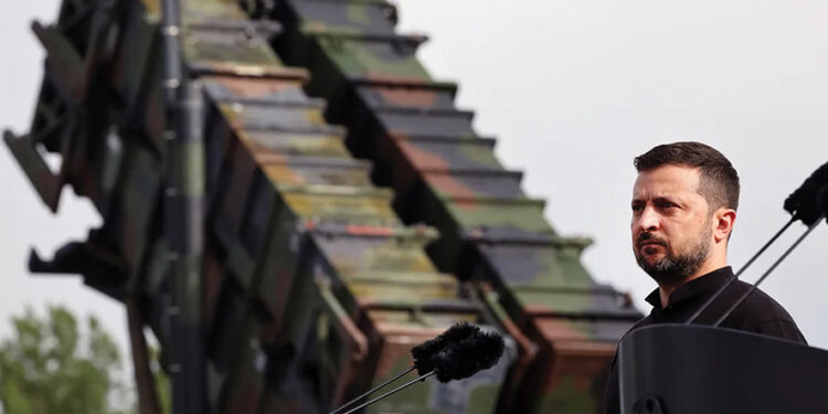 President Volodymyr Zelensky stands in front of a Patriot anti-aircraft missile system in Germany in 2024. Photo by Jens Buttner / Getty Images
