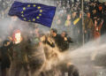 Protesters holding an EU flag are sprayed with a water cannon during clashes with riot police near the Georgian parliament in Tbilisi. Source: AFP