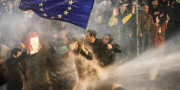 Protesters holding an EU flag are sprayed with a water cannon during clashes with riot police near the Georgian parliament in Tbilisi. Source: AFP