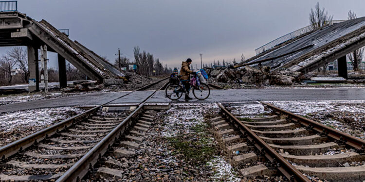 A man in Pokrovsk carries his belongings on a bicycle past a bridge destroyed by Russian shelling. Photo by Anton Shtuka for NPR