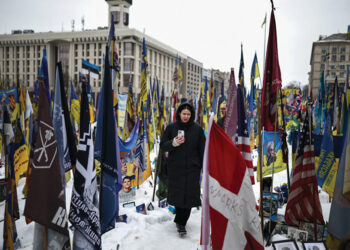A person walks through a makeshift memorial to fallen Ukrainian and foreign soldiers in Kyiv. Photo by Henry Nicholls/AFP/Getty Images