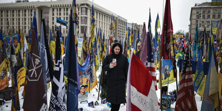 A person walks through a makeshift memorial to fallen Ukrainian and foreign soldiers in Kyiv. Photo by Henry Nicholls/AFP/Getty Images