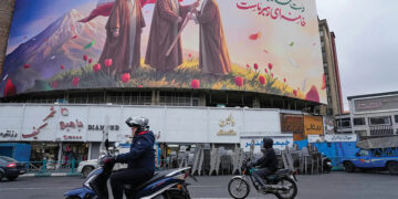 A billboard depicting Iran’s late Supreme Leader Ayatollah Ali Khamenei handing the country’s flag to his son and successor Ayatollah Mojtaba Khamenei. Source: AP Photo/Vahid Salemi